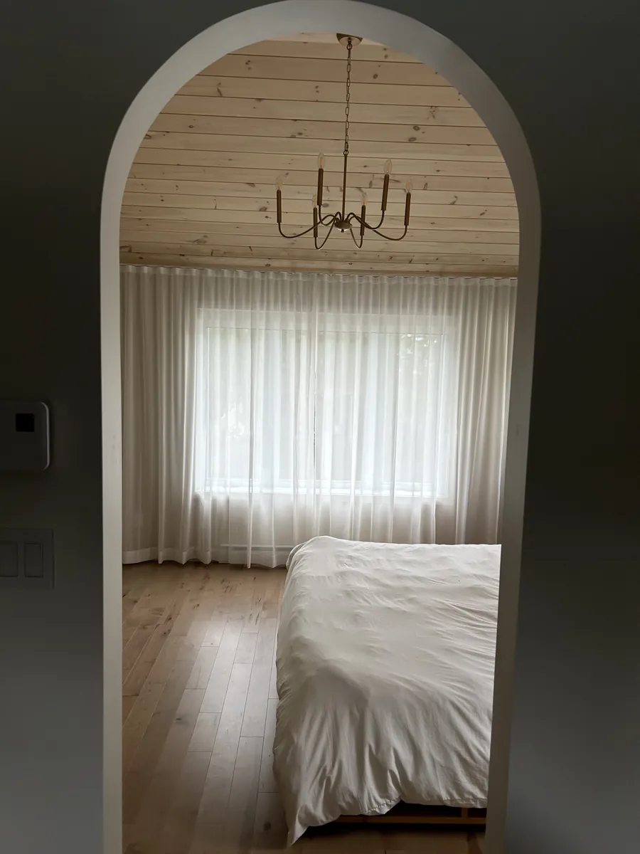 Voilage ripplefold dans la chambre des maîtres, vu à travers une porte en arche